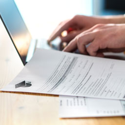 Papers lie beside a laptop