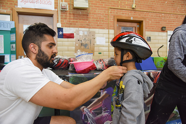 Medical student Al-Karim Gilani fits 4-year-old Michael Cruz with a free helmet provided by the Texas Medical Association.