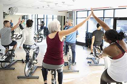 Two women high-five in a cycling class